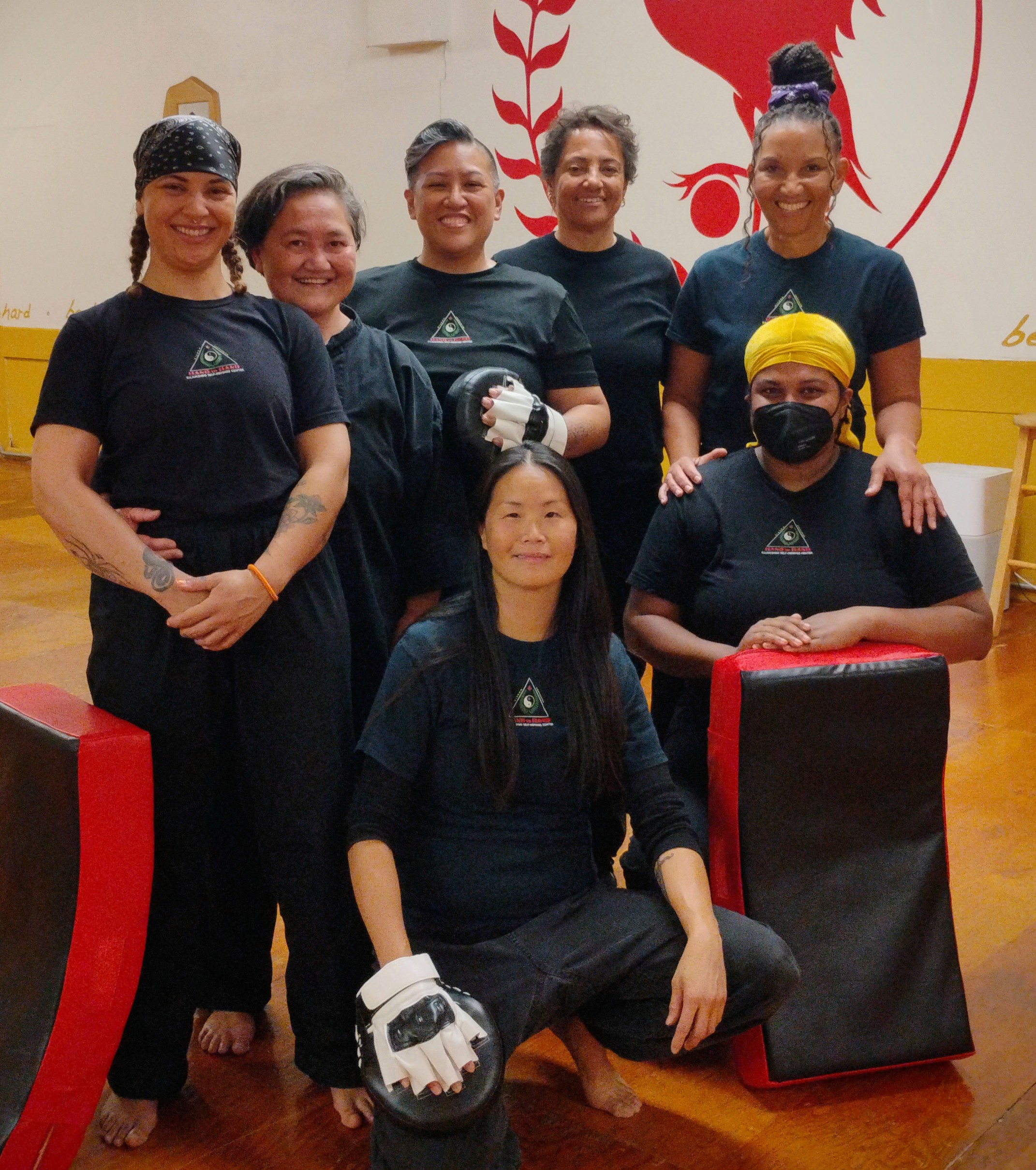 BIPOC Self Defense Class Group of smiling people in H2H shirts with martial arts pads